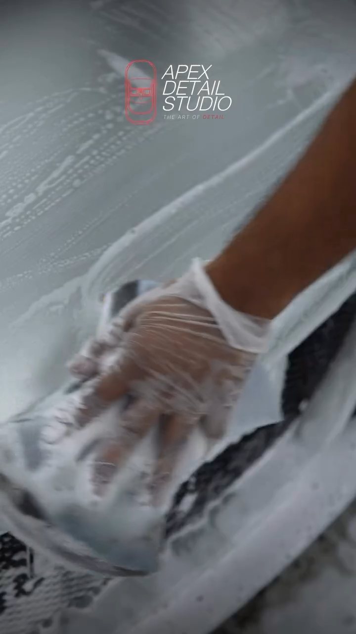 Close-up of a gloved hand washing a Lotus Exige panel at Apex Detail Studio