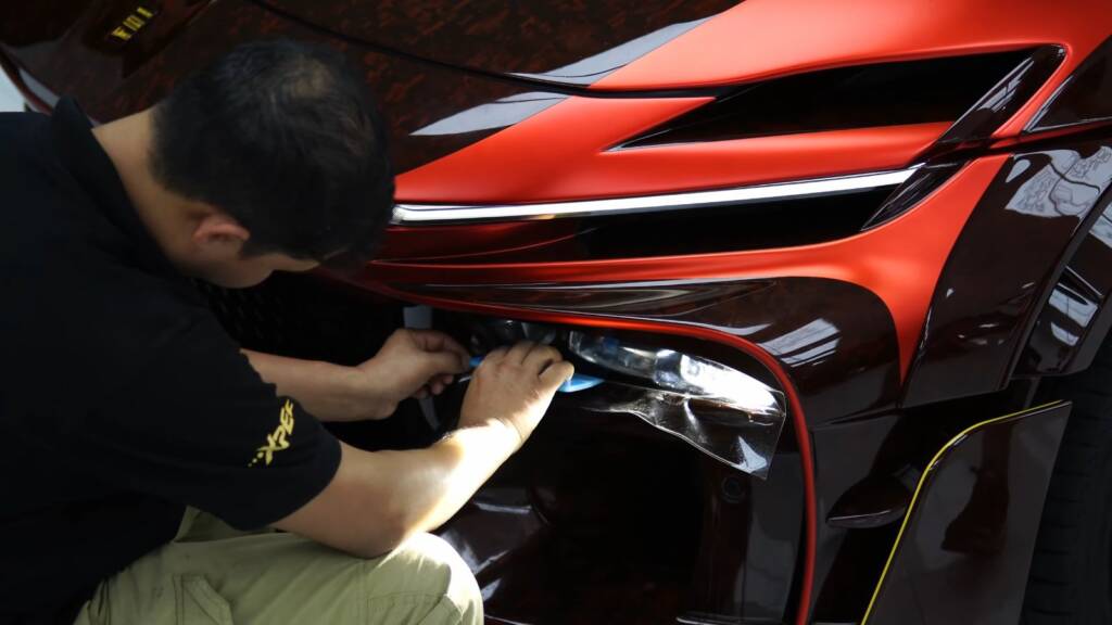 Installer fitting premium PPF on a Mansory Pugnator front bumper