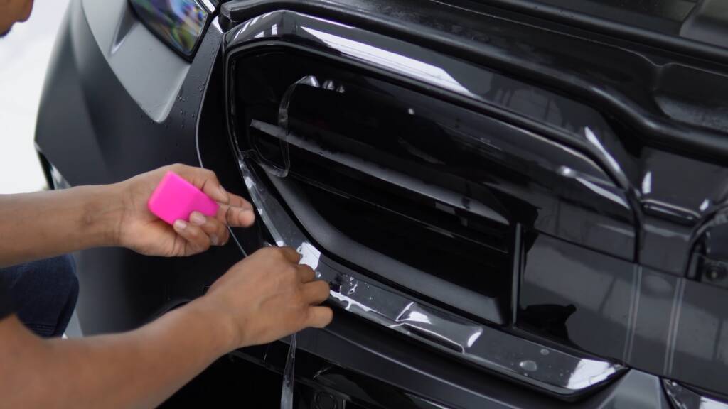 Matte PPF being trimmed around the front grille of a BMW M5 Touring at Apex Dubai
