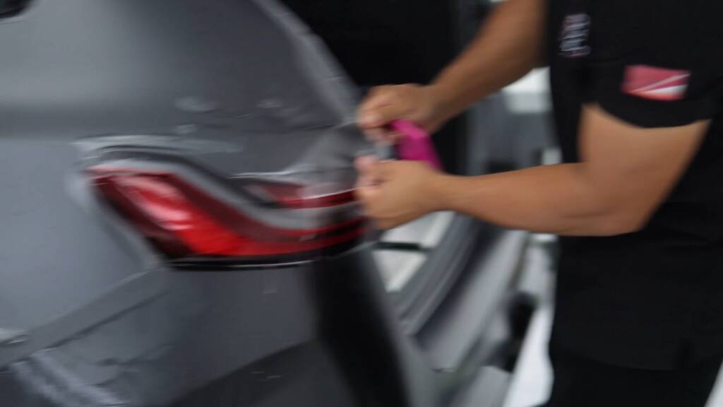 Installer working matte PPF around the tail light of a BMW M5 Touring in Dubai