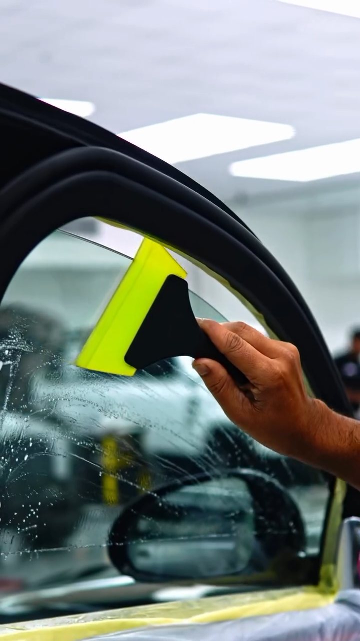 Squeegeeing window tint on the Maybach S580 door glass in Dubai