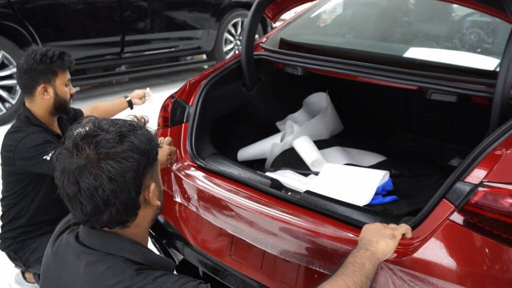Two installers working on a Mercedes-AMG CLA with the boot open