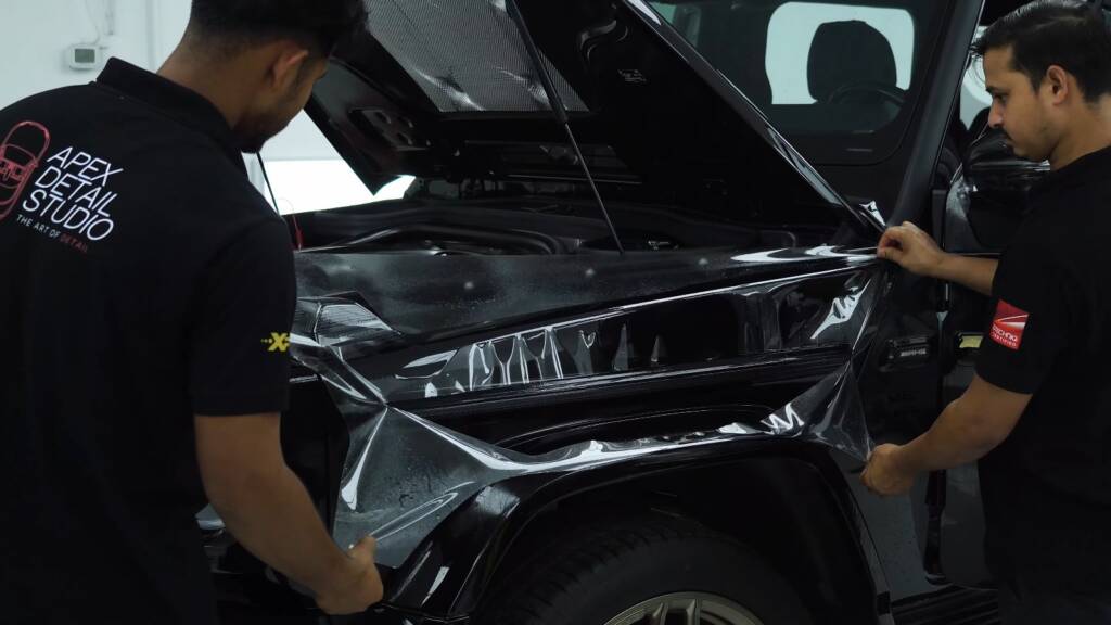 Two installers fitting PPF to a Mercedes-AMG G63 front bumper