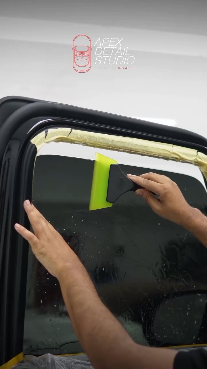 Installer squeegeeing window tint on the Mercedes-AMG G63 door glass at Apex Detail Studio Dubai