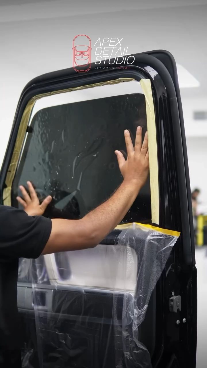 Hands smoothing tint film on the Mercedes-AMG G63 window at Apex Detail Studio