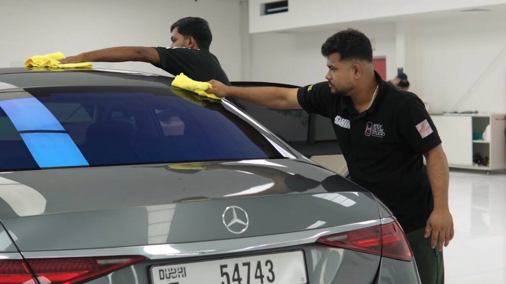 Two Apex detailers giving a grey Mercedes S500 a final wipe down after PPF