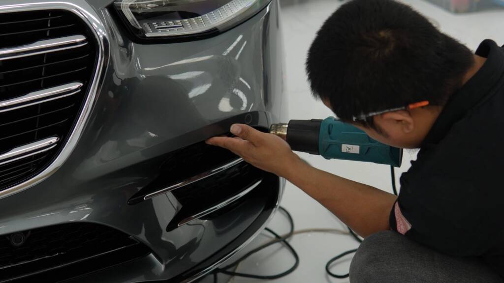 Installer using heat to shape PPF on the front bumper of a Mercedes S500