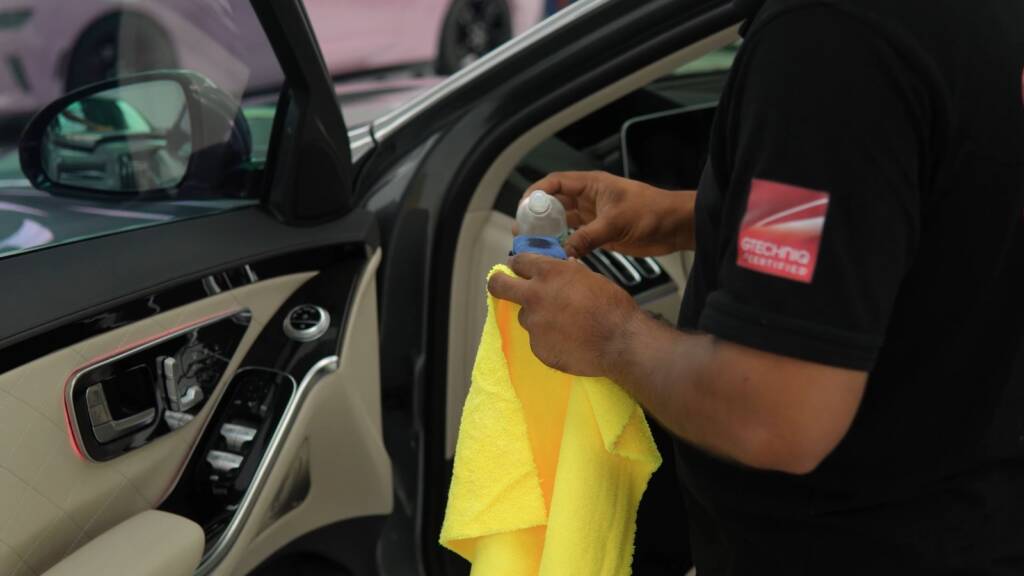 Detailer cleaning the interior door card of a Mercedes-Benz S500 before handover