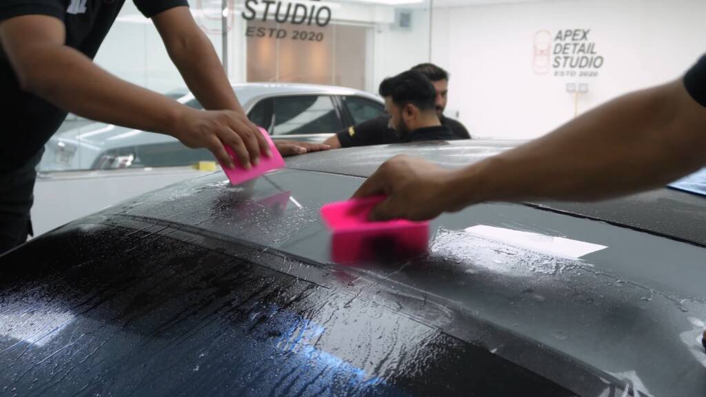 Installers squeegeeing PPF across the rear of a Mercedes S500 at Apex Dubai