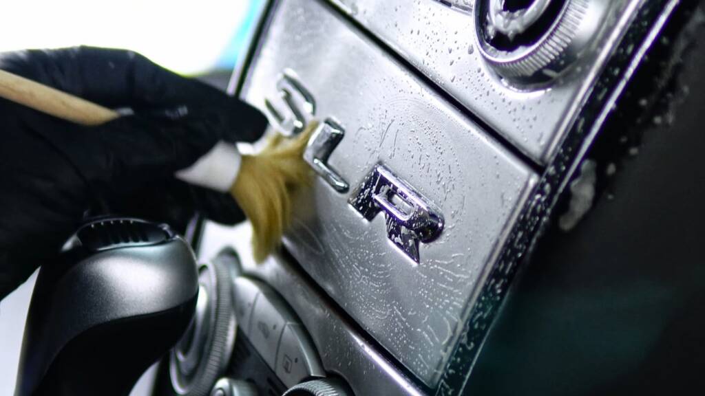 Brushing dust from the SLR centre console of a Mercedes-Benz SLR McLaren during interior detailing in Dubai