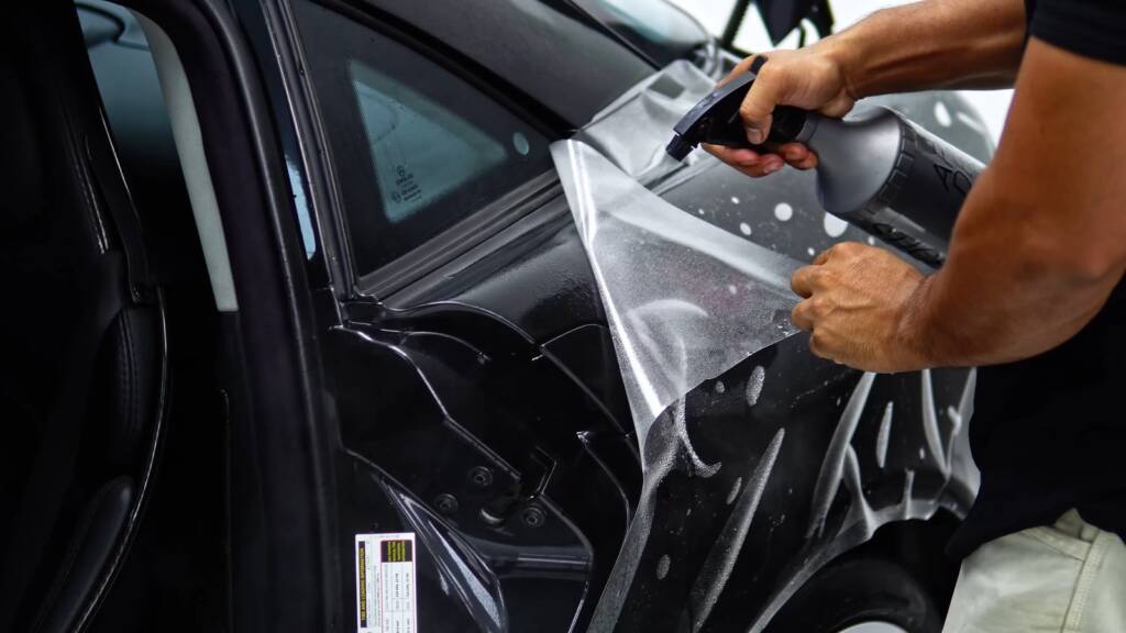 Installers laying paint protection film on a black Mercedes-Benz SLR McLaren at Apex Detail Studio Dubai