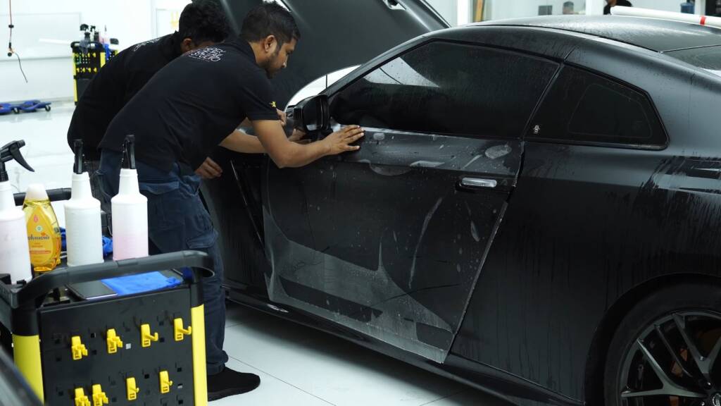 Two installers fitting stealth PPF to a Nissan GTR door