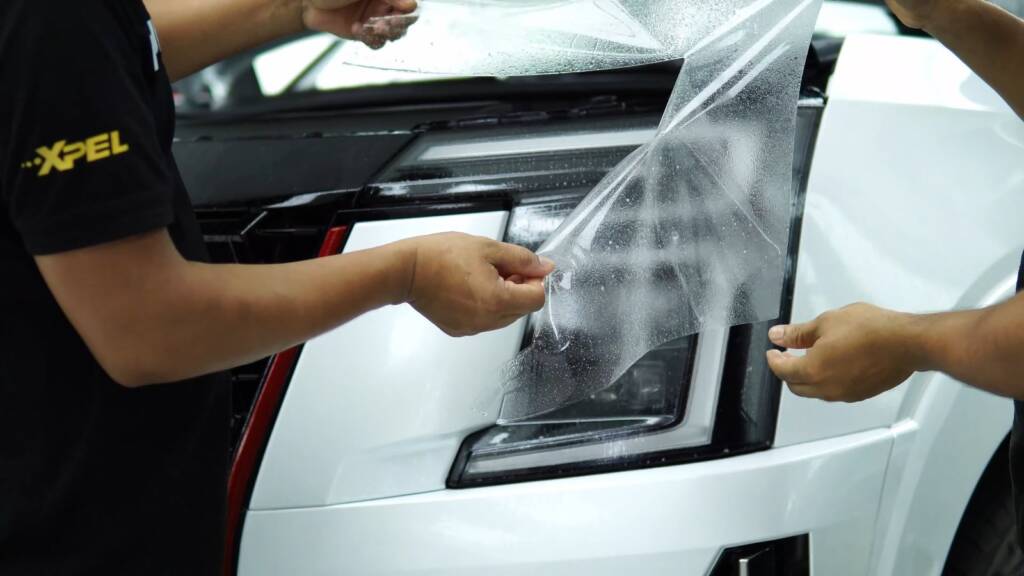 Two installers fitting PPF to a Nissan Patrol Nismo front bumper