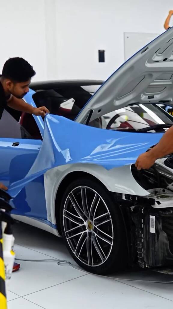 Front bumper removed so blue colour PPF wraps the wing edges of a Porsche 911 Carrera