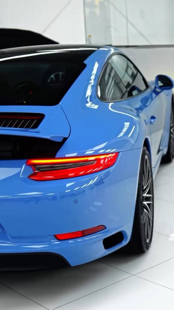 Rear three quarter of the Porsche 911 Carrera in blue colour change PPF with tinted windows in Dubai