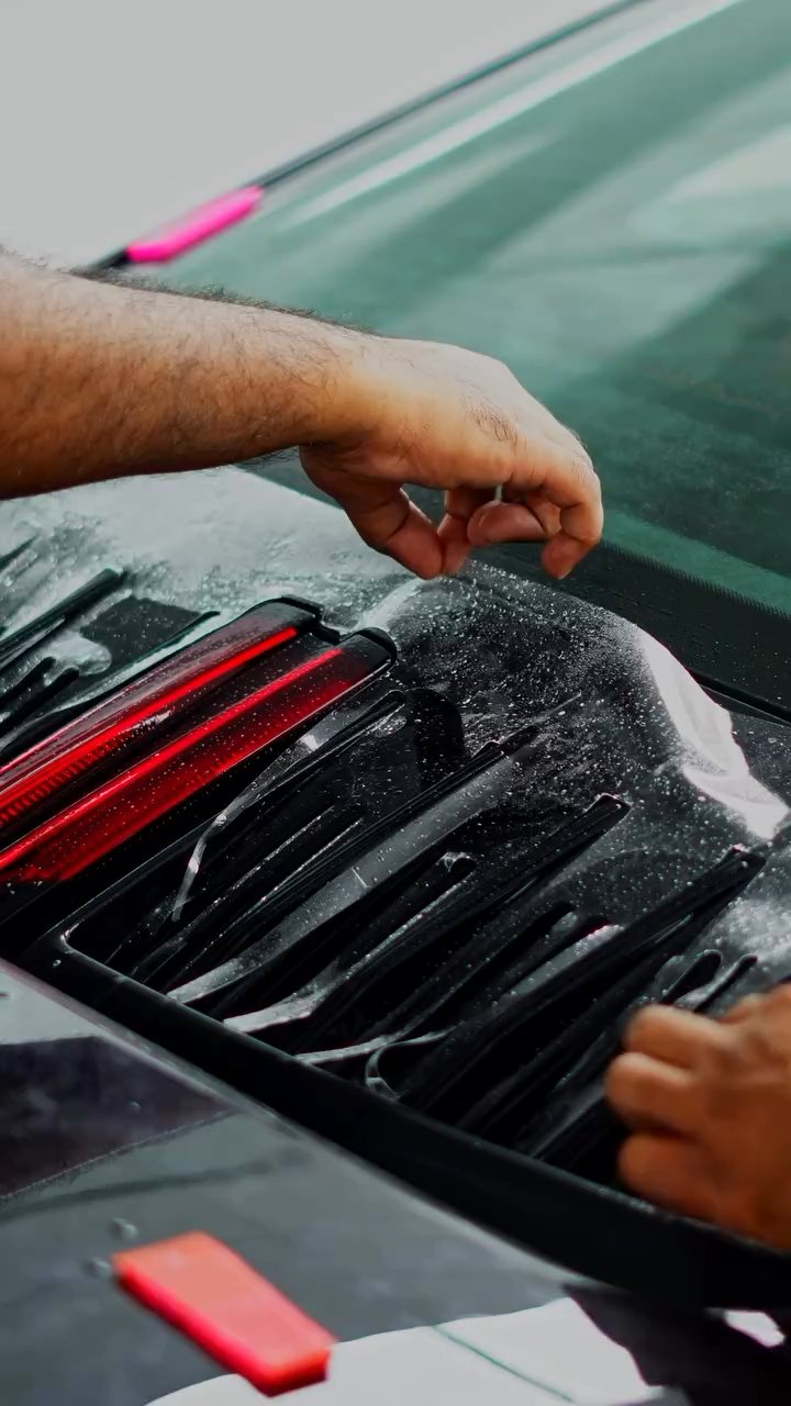 Installer fitting PPF around the Porsche 911 rear engine grille in Dubai