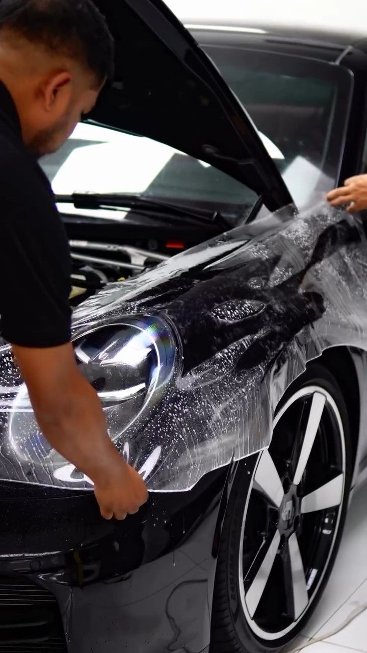 Installer fitting PPF over the black Porsche 911 Carrera front wing in Dubai