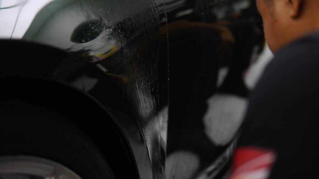 Installer working PPF into the front wing curves of a Porsche 911 GT3 Touring at Apex Dubai