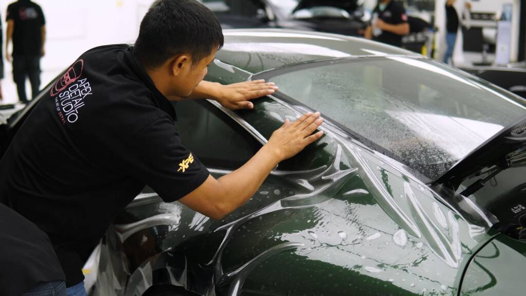 Installer laying PPF on a green Porsche 911 GT3 Touring in the Apex Detail Studio Dubai bay