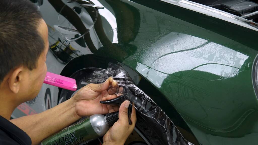 Installer working PPF around the headlight of a new Porsche 992.2 GT3 at Apex Dubai