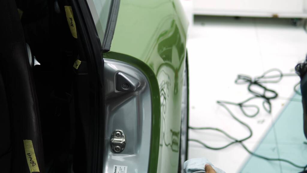 Installer finishing green colour PPF in the door shut of a Porsche 911 997 in Dubai