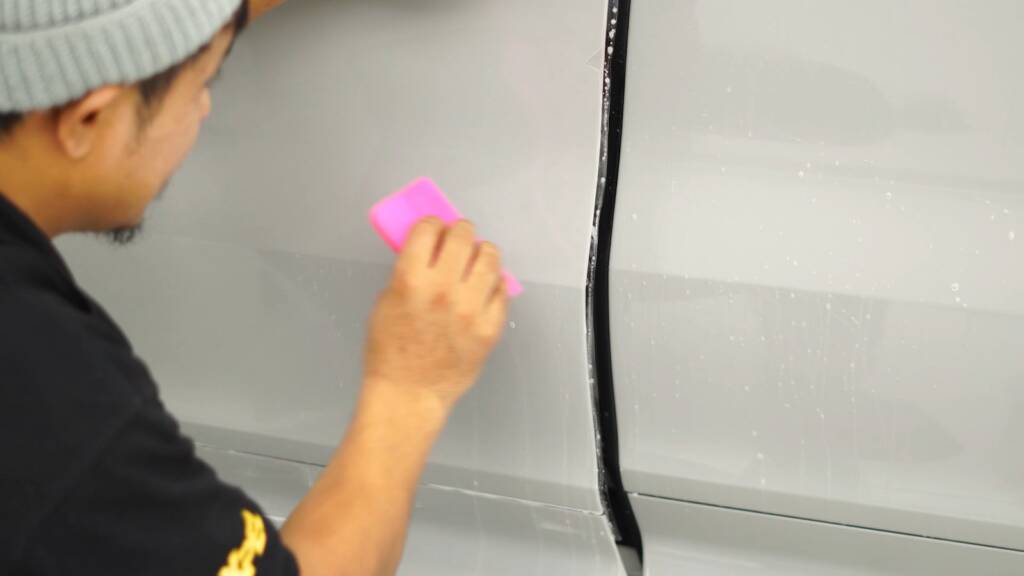 Installer squeegeeing PPF on a Porsche Cayenne GTS door
