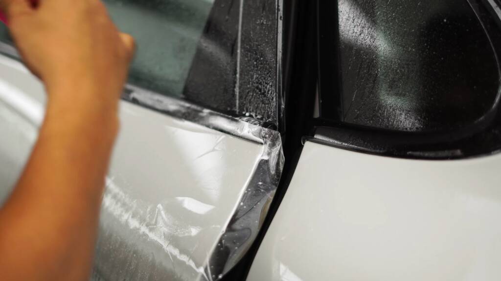 Installer fitting PPF near the mirror of a 2026 Porsche Cayenne GTS at Apex Dubai