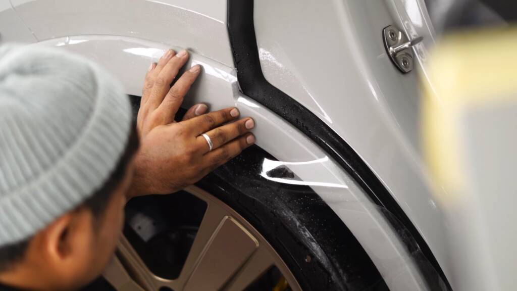 Installer finishing PPF at the rear arch edge of a Porsche Cayenne GTS