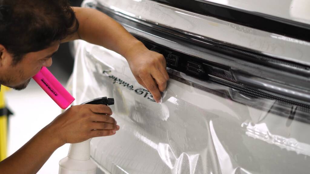 Installer trimming PPF along the trim of a Porsche Cayenne GTS