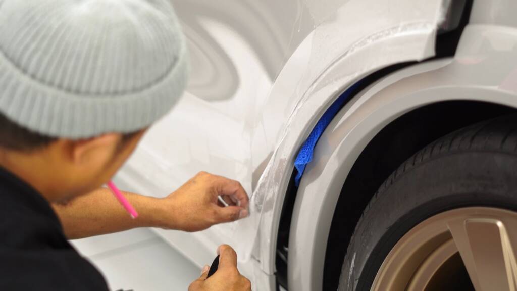 Installer wrapping PPF around the wheel arch of a Porsche Cayenne GTS