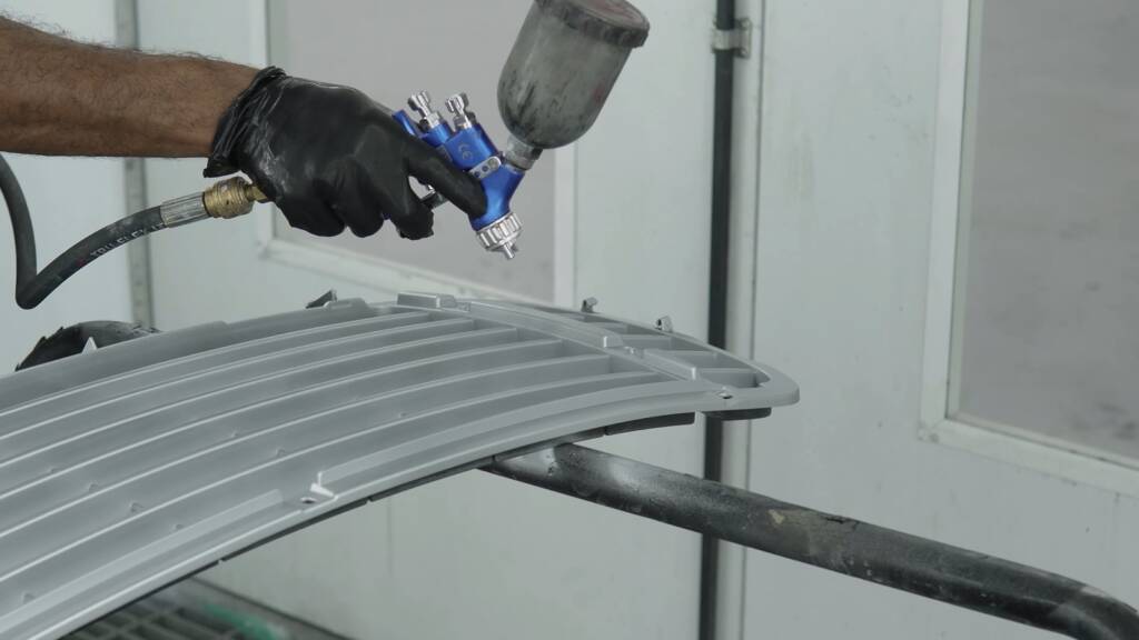 Porsche Cayenne front grille receiving a silver coat in the spray booth