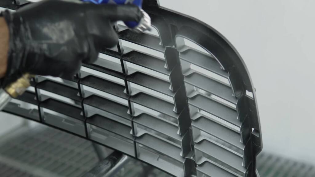 Technician spraying the Porsche Cayenne grille slats silver