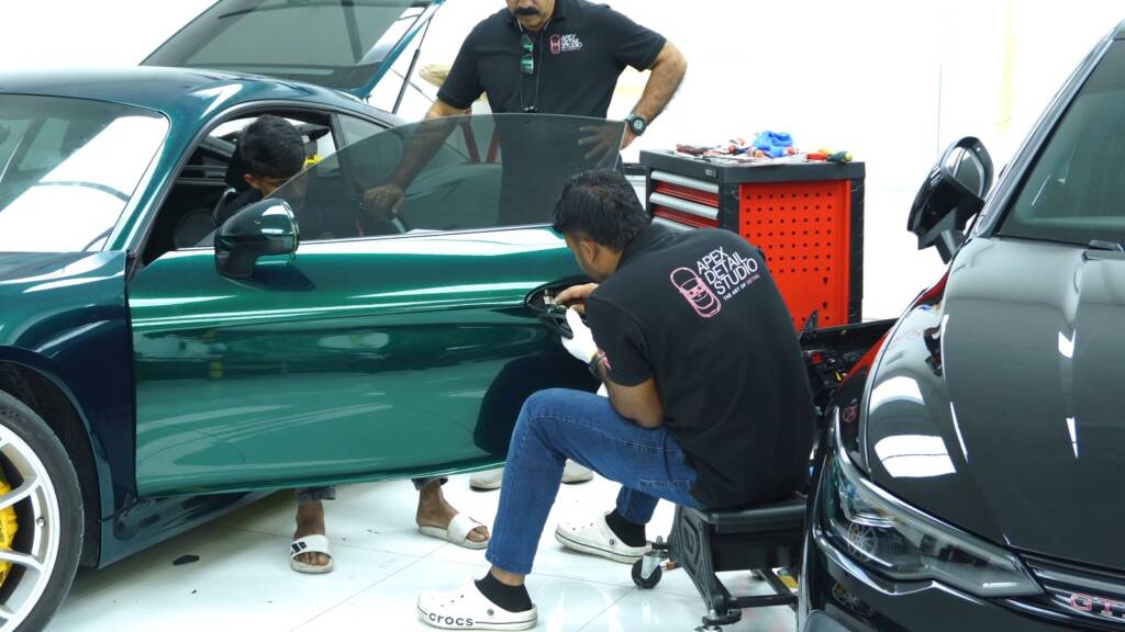 Installers working on a Porsche Cayman GT4 door during a colour change in Dubai