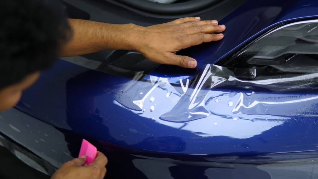 PPF being smoothed near the headlight of a Porsche Taycan
