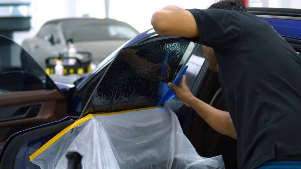 Installer fitting tint to the side window of a Porsche Taycan