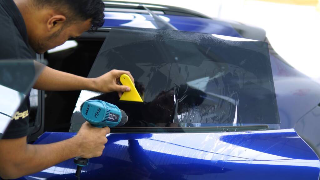Window tint being heat-shaped on the glass of a Porsche Taycan