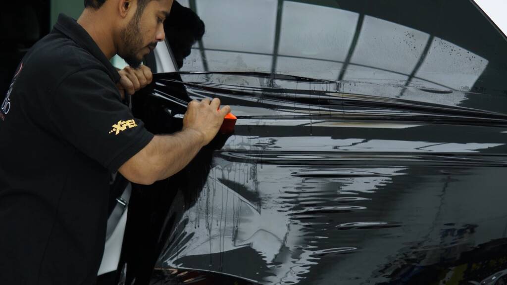 Installer fitting gloss black colour PPF to the door of a Range Rover