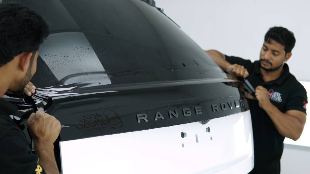 Installer fitting gloss black colour PPF on the rear quarter of a Range Rover