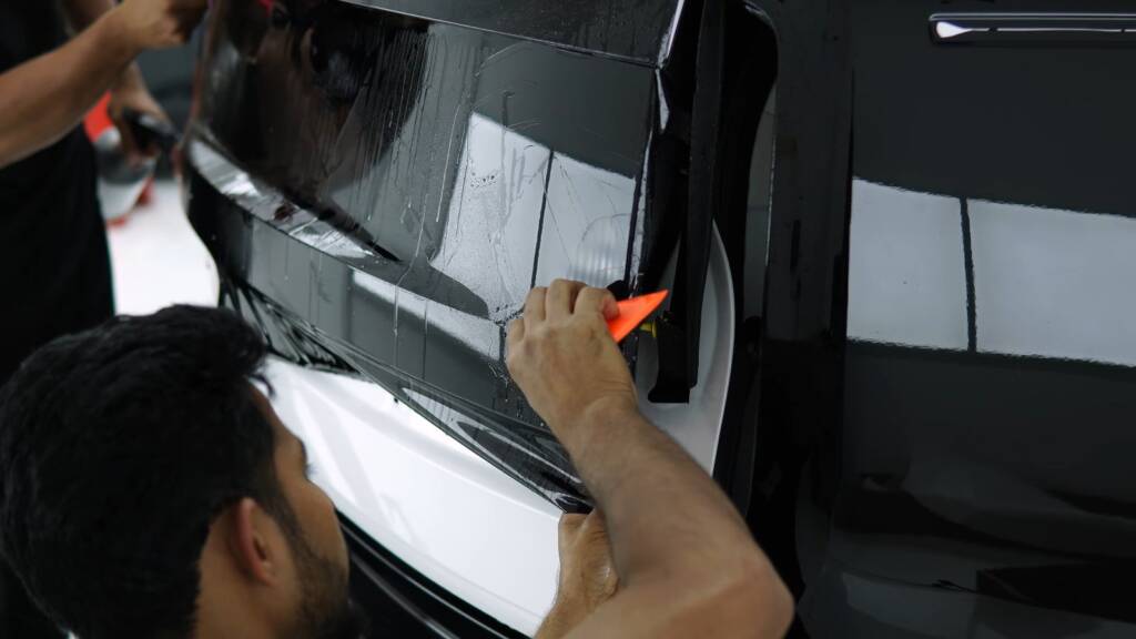 Gloss black colour PPF being trimmed around a Range Rover window