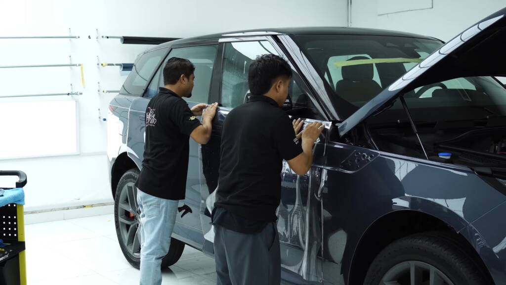 Two installers fitting PPF to a Range Rover Sport door