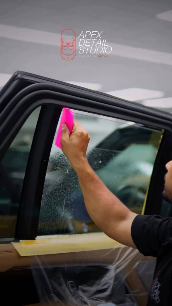 Squeegeeing window tint on the Range Rover door glass at Apex Detail Studio