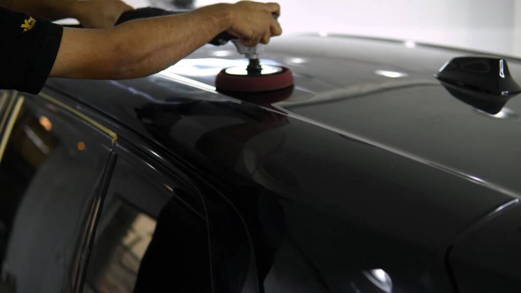 Polishing the roof of a black Rolls-Royce Cullinan