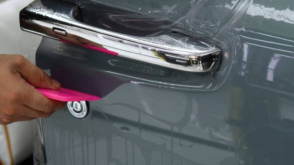 Clear PPF being fitted around the chrome door handle of a Rolls-Royce Ghost
