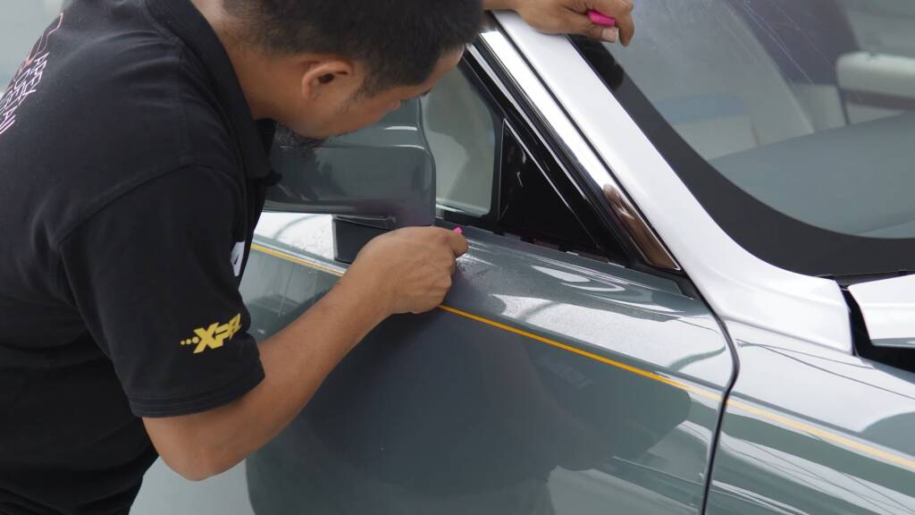 Installer finishing the two-tone line along the door of a Rolls-Royce Ghost