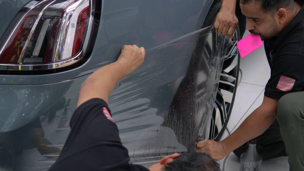 Installers fitting clear PPF on the rear quarter of a Rolls-Royce Ghost