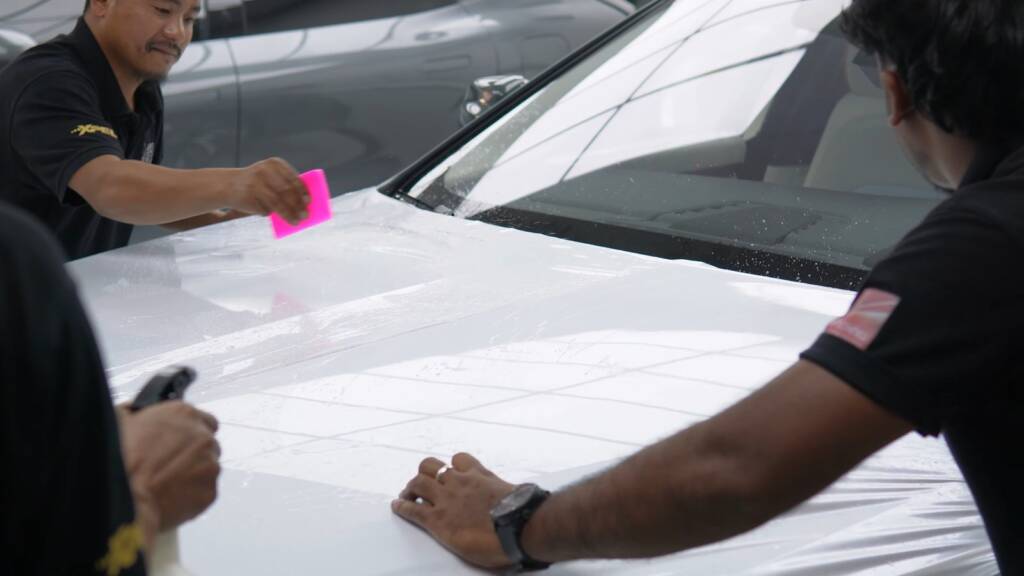 Installers laying white colour PPF on the roof of a Rolls-Royce Ghost