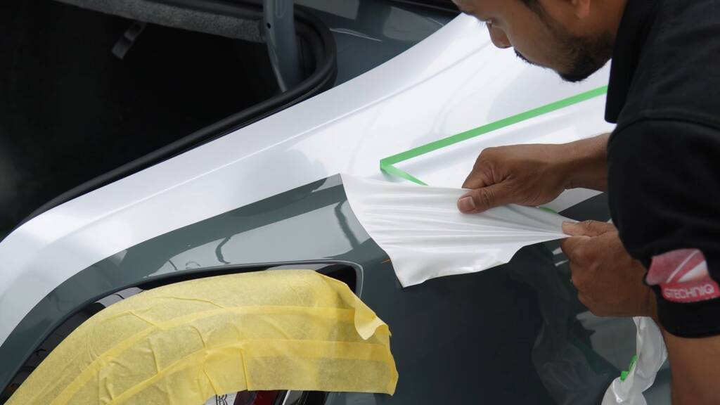 Installer trimming white colour PPF along the two-tone line of a Rolls-Royce Ghost