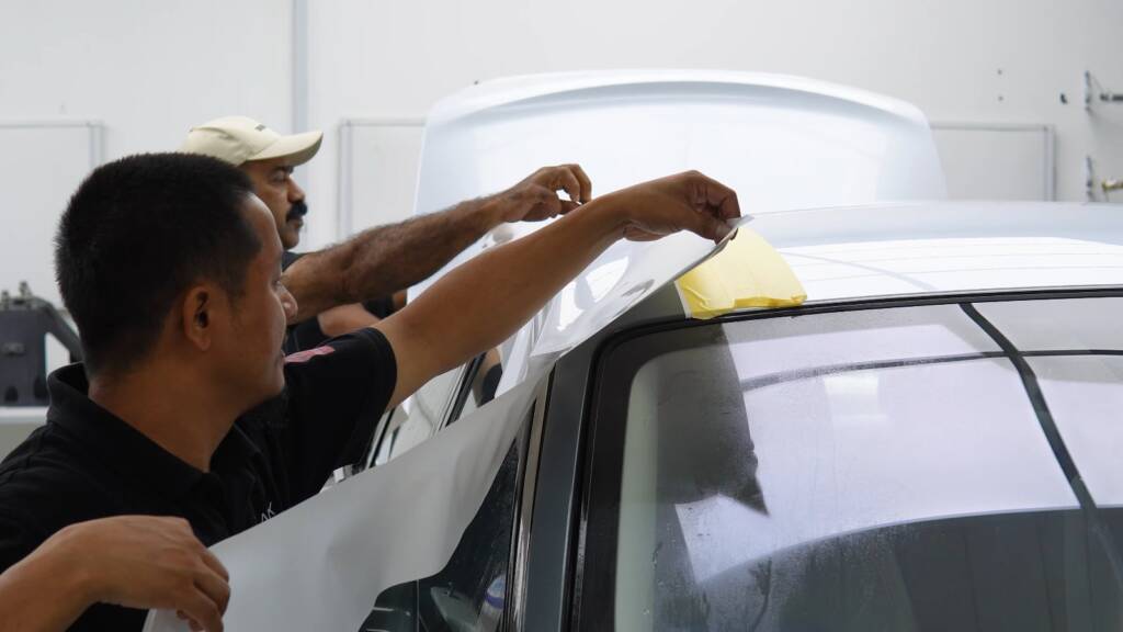 Apex team stretching white colour PPF across the roof of a Rolls-Royce Ghost