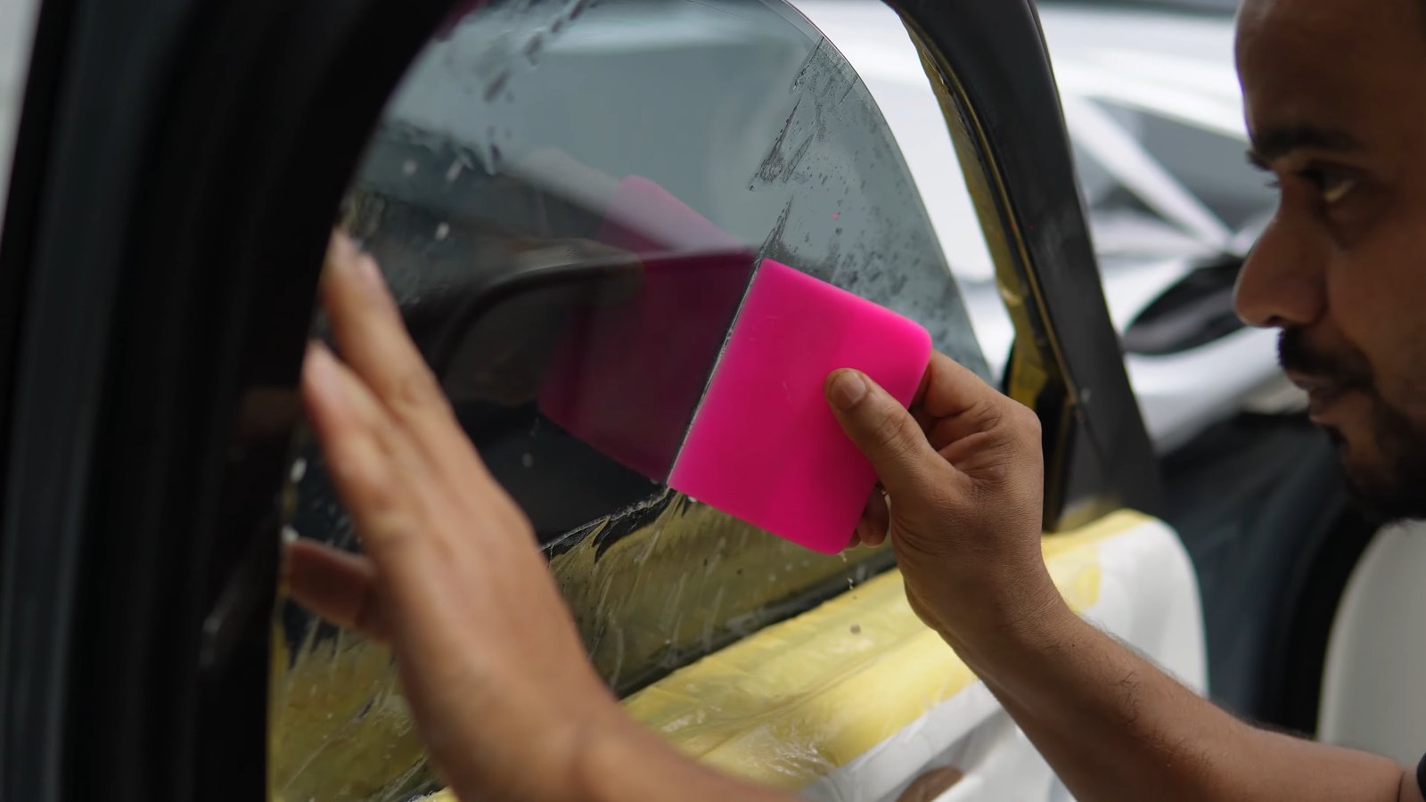 Squeegee pushing water from under window film on a Rolls-Royce Ghost