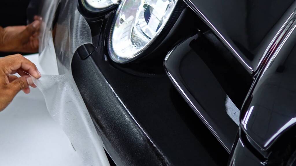 PPF installer squeegeeing film around the headlight and front bumper of a Mercedes SLR McLaren in Dubai